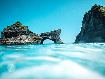Split Level View of Natural Rock Arch and Cliffs in Turquoise Ocean