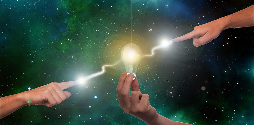 Conceptual teamwork image with hands creating a glowing lightbulb idea