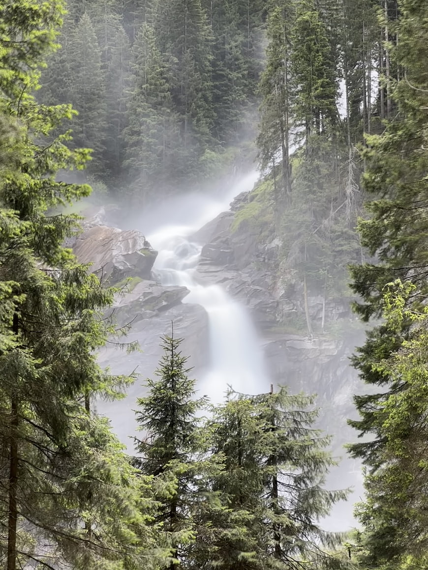 Misty waterfall cascading through a dense evergreen forest landscape