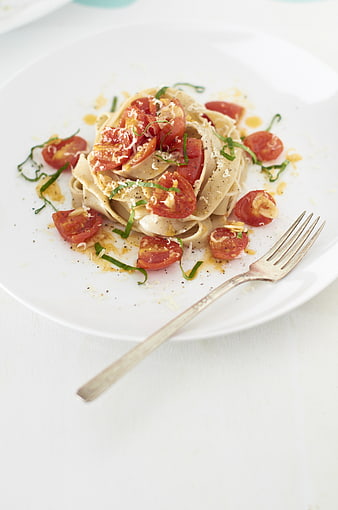 Gourmet Pasta with Tomatoes and Basil on White Plate