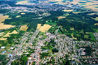 Aerial view of suburban town surrounded by green fields and forests