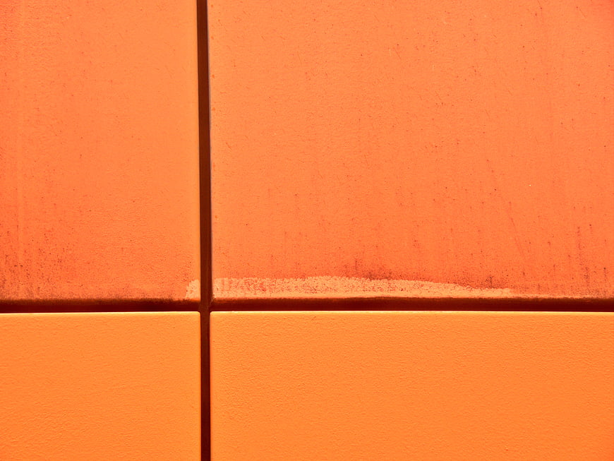Close-up of textured orange wall tiles with grout lines