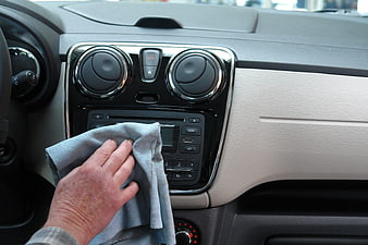 Hand cleaning car dashboard with microfiber cloth