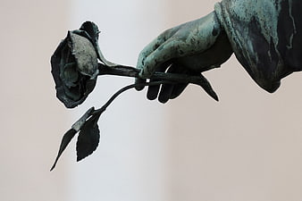 Close-up of bronze angel hand holding a rose sculpture