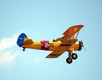 Vintage U.S. Navy Biplane Flying in Blue Sky