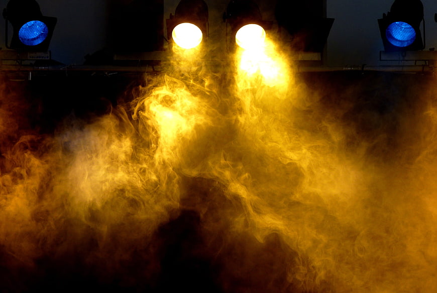 Yellow stage lights shining through thick smoke and fog
