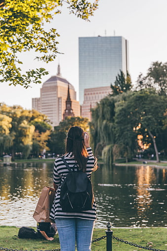 Woman Taking Photo of City Skyline from Park Lake