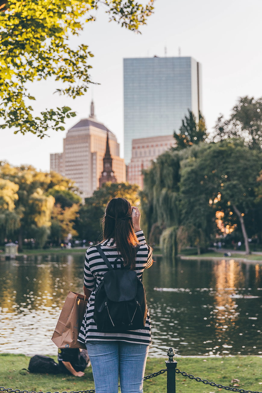 Woman Taking Photo of City Skyline from Park Lake