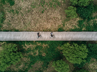 Aerial view of two cyclists riding on a wooden bridge