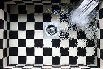 Water Flowing into Black and White Checkered Sink Drain