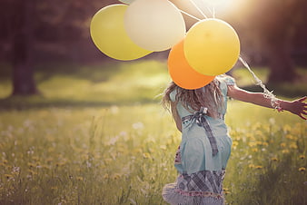 Little Girl Running with Balloons in a Sunny Meadow