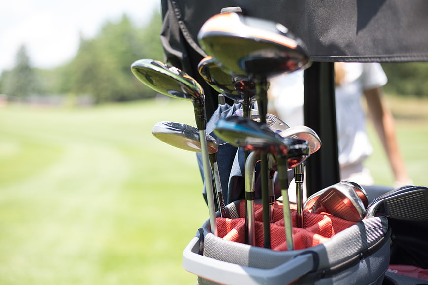 Golf clubs in a bag on a sunny golf course