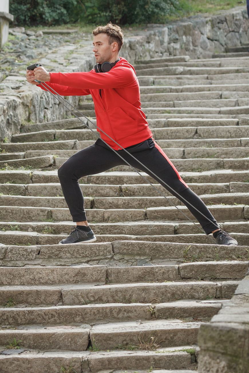Athletic Man Training with Resistance Bands on Stone Steps