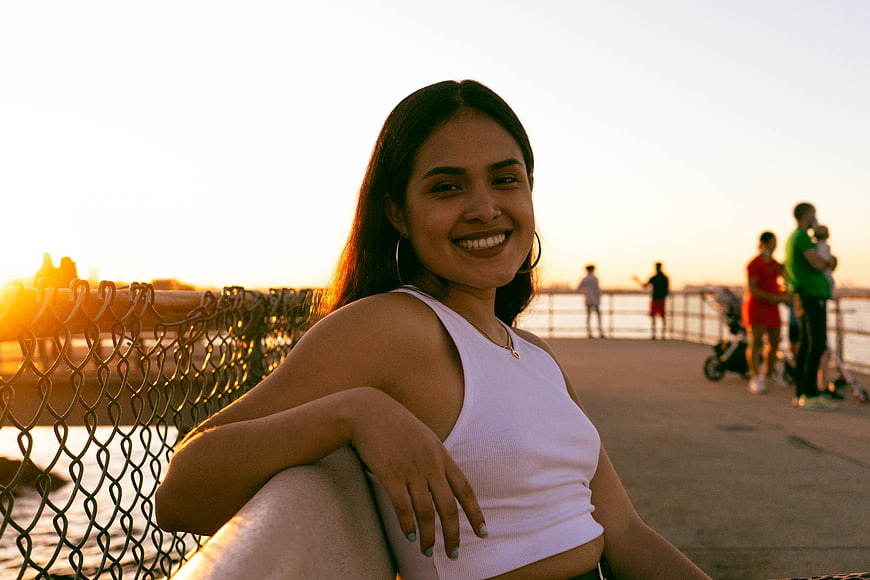 Smiling Woman Leaning on Pier Railing at Sunset