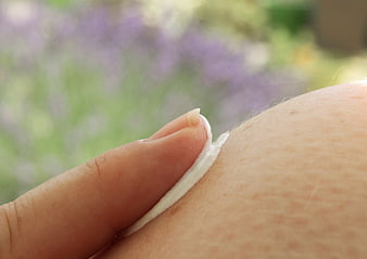 Close-up of hand applying white sunscreen cream to skin outdoors