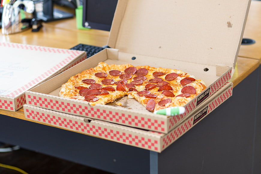 Pepperoni pizza in open box on office desk