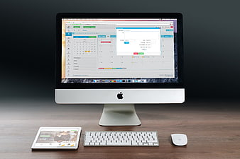 Apple iMac, iPad, and keyboard on wooden desk workspace