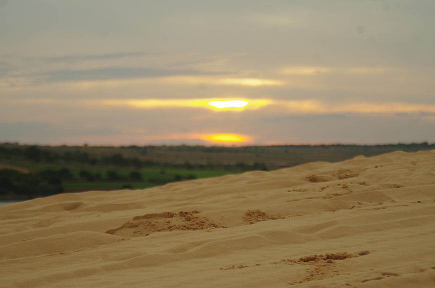 Golden Sunset Over Sand Dunes and Green Landscape