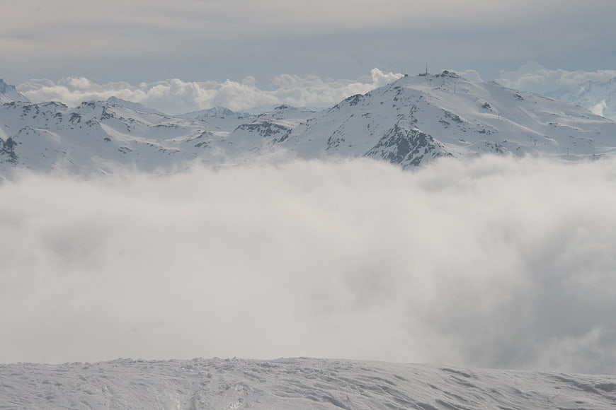 Snowy mountain peaks rising above a thick sea of clouds