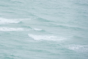 Aerial view of gentle turquoise ocean waves with white foam
