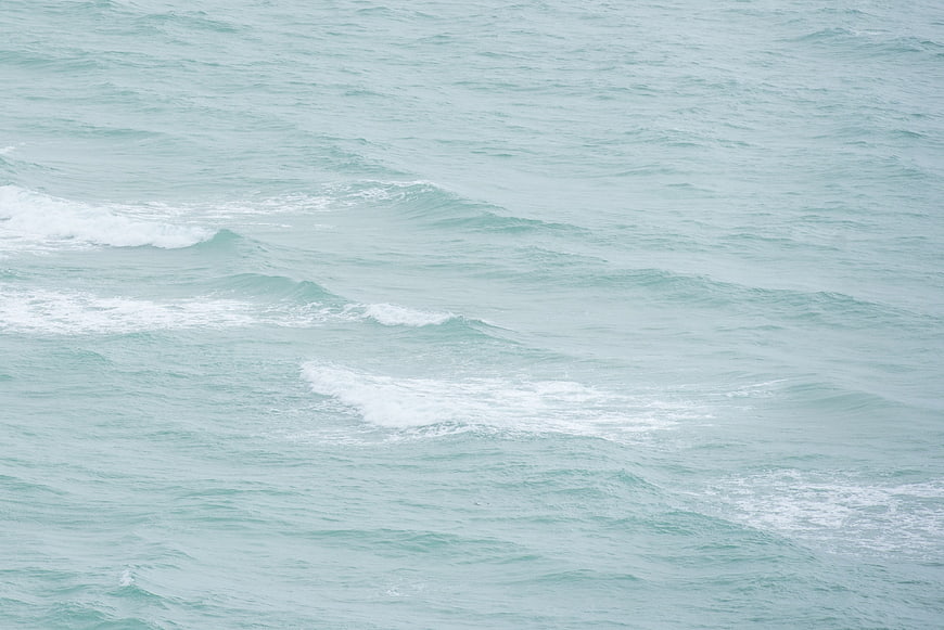 Aerial view of gentle turquoise ocean waves with white foam