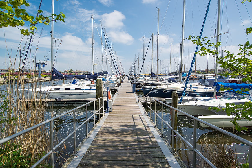 Wooden pier in marina with sailboats on sunny day