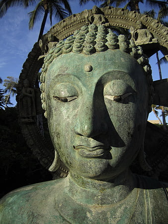 Close-up of weathered bronze Buddha statue face outdoors
