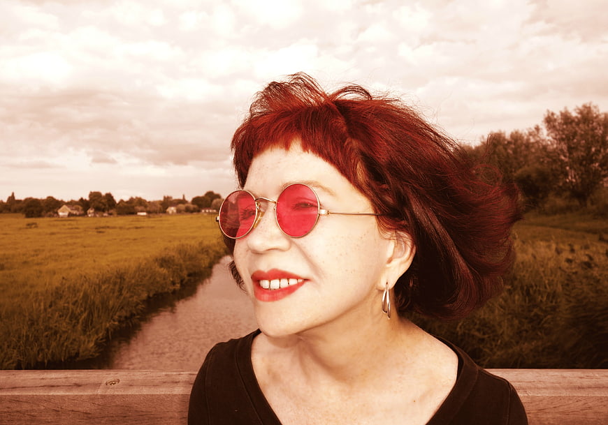 Senior woman with red hair and sunglasses smiling outdoors