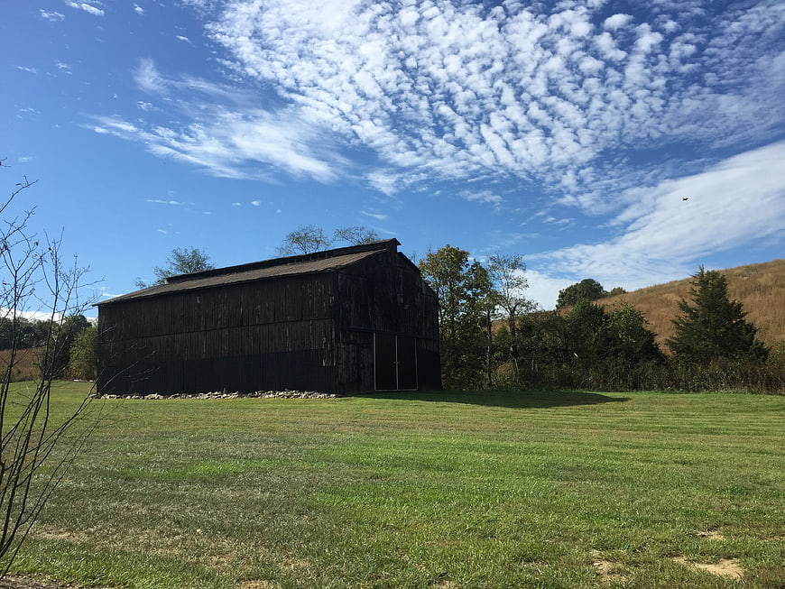 Old weathered barn in green field under blue sky