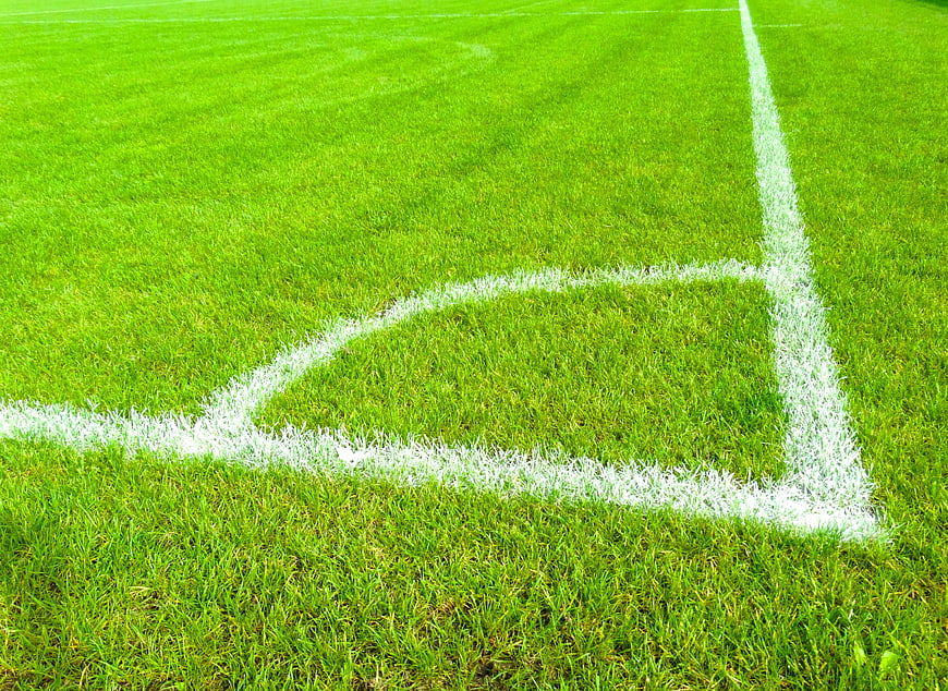 Green soccer field corner with white lines