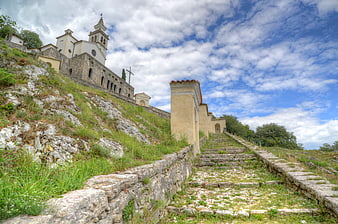 Stone staircase leading to historic church on grassy hill
