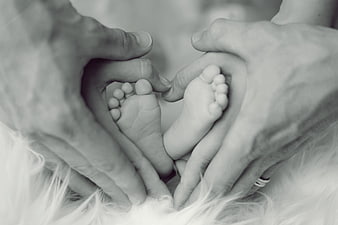 Parents forming heart shape around newborn baby feet