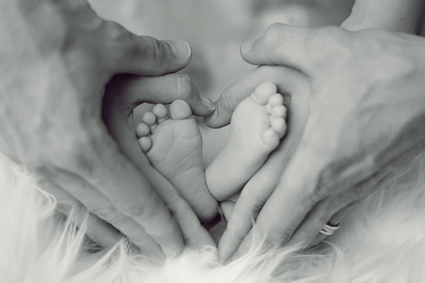 Parents forming heart shape around newborn baby feet