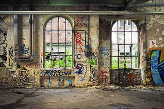 Abandoned industrial interior with arched windows and colorful graffiti