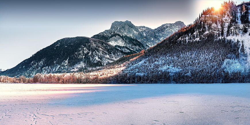 Sunlit Frozen Lake with Snowy Mountain Peaks