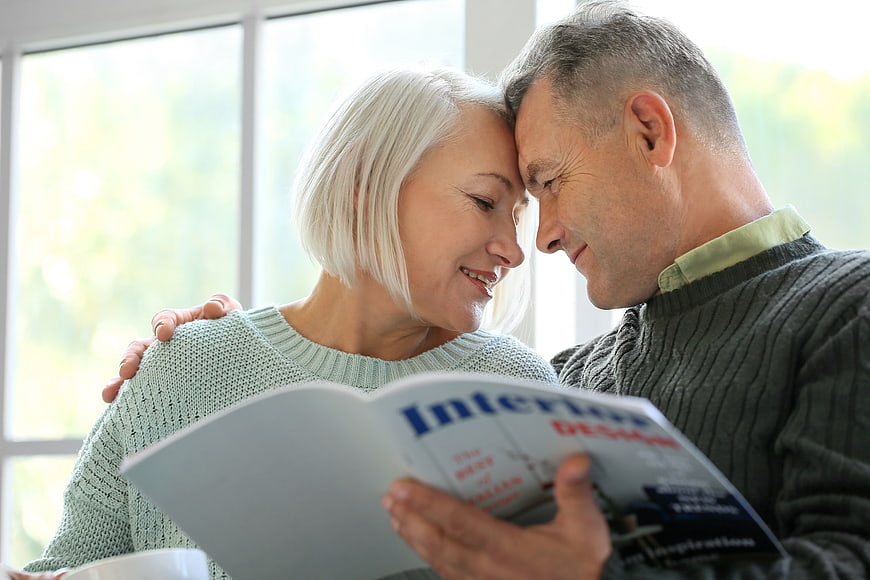 Senior couple reading interior design magazine together at home