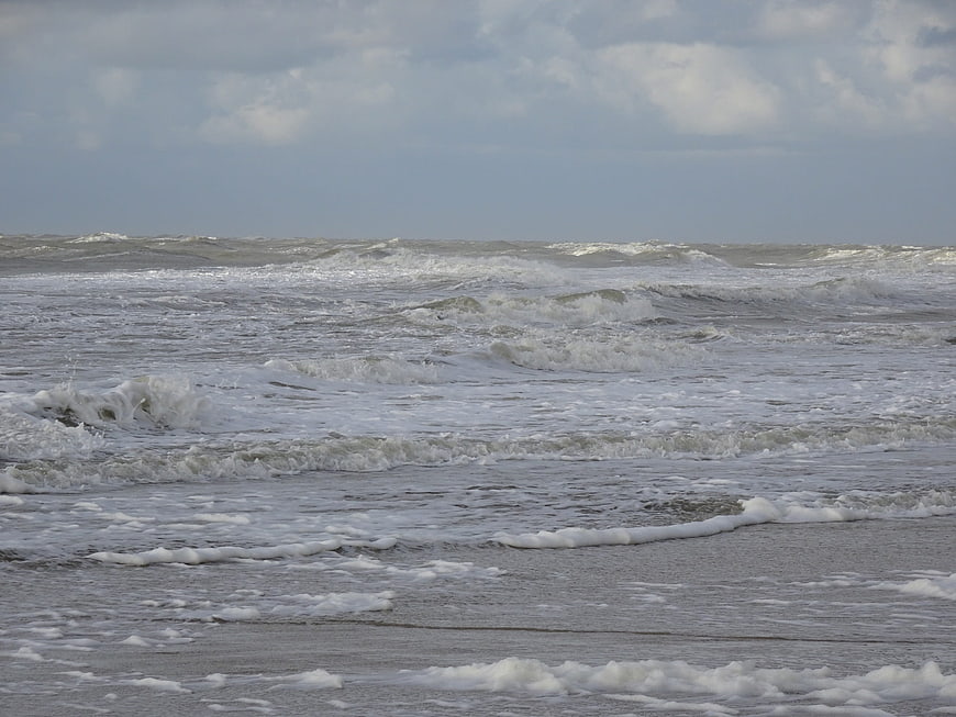 Rough gray ocean waves crashing on a cloudy beach