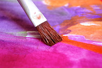 Close-up of paintbrush on colorful watercolor paper texture