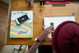 Student studying at wooden desk with Dr. Seuss book and smartphone