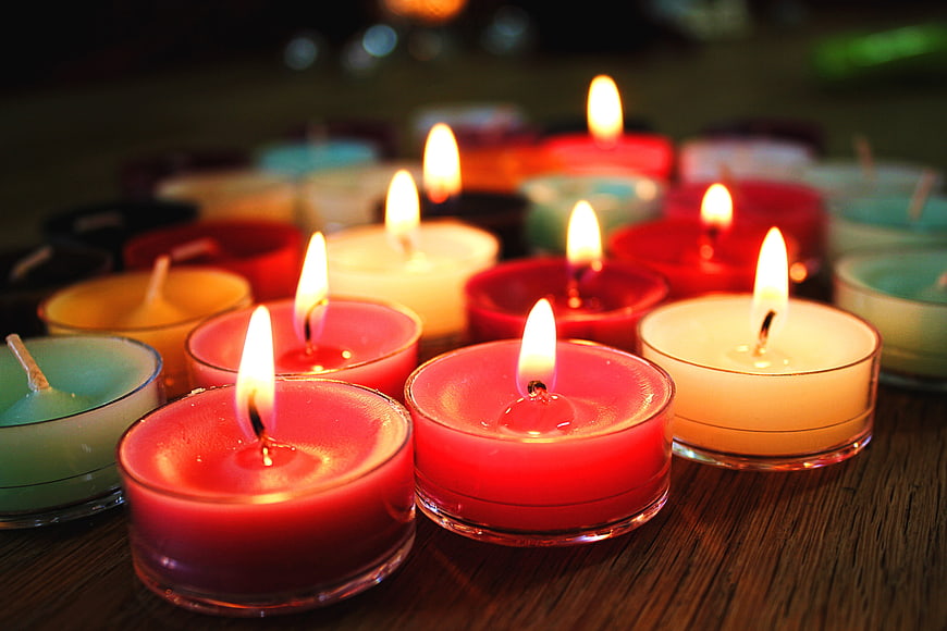 Colorful Tealight Candles Burning on Wooden Table