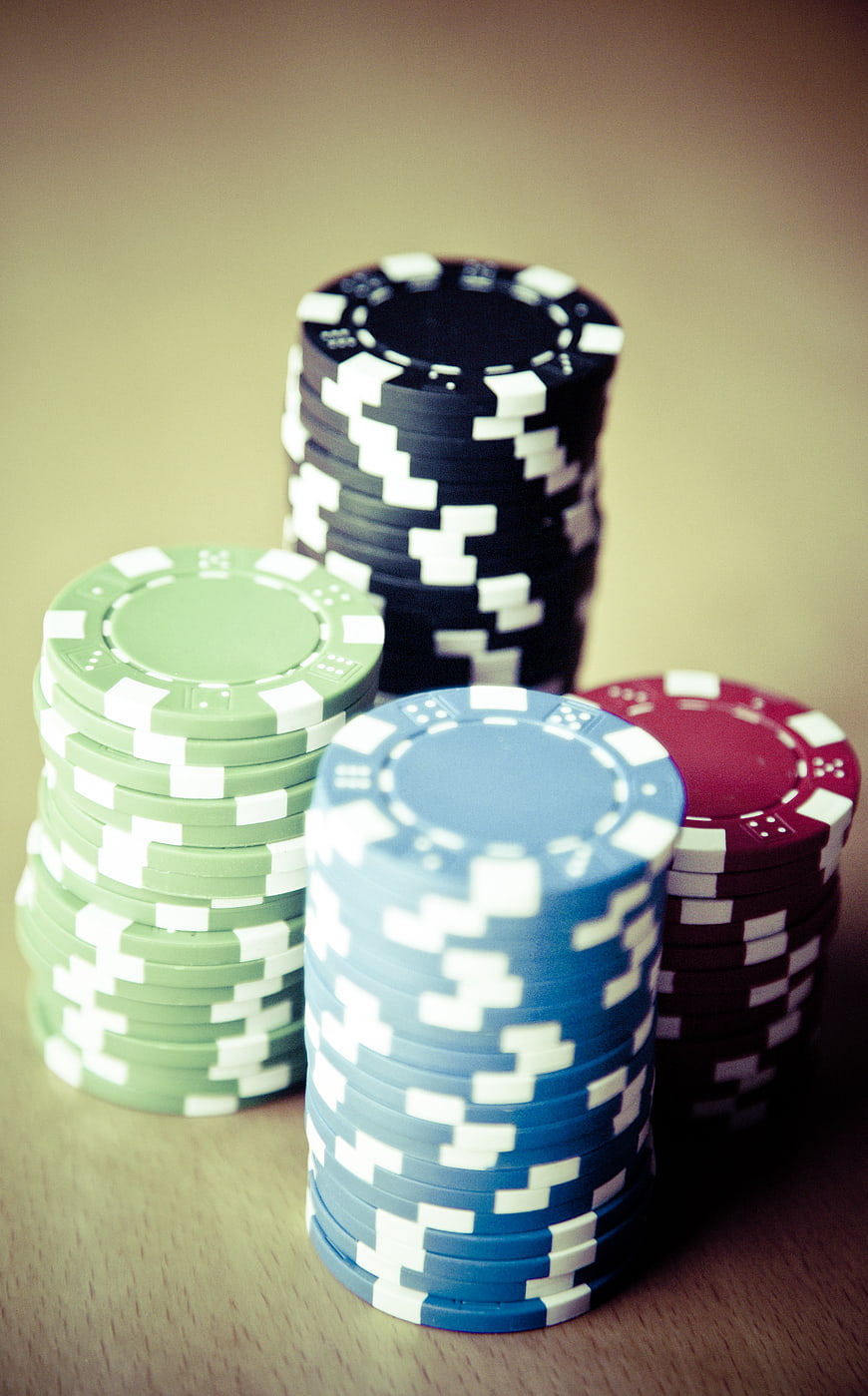 Stacks of colorful poker chips on wooden table