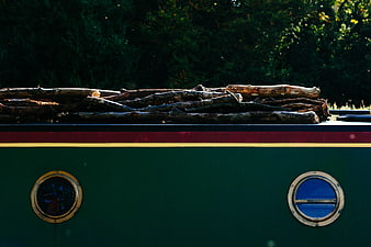 Vintage green boat with logs on roof and porthole windows