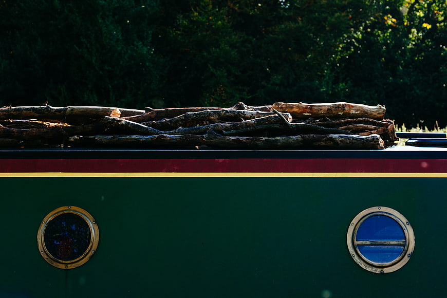 Vintage green boat with logs on roof and porthole windows