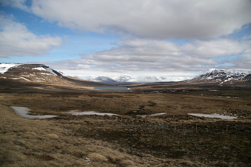 Vast Highland Landscape with Snow-Capped Mountains and Cloudy Sky