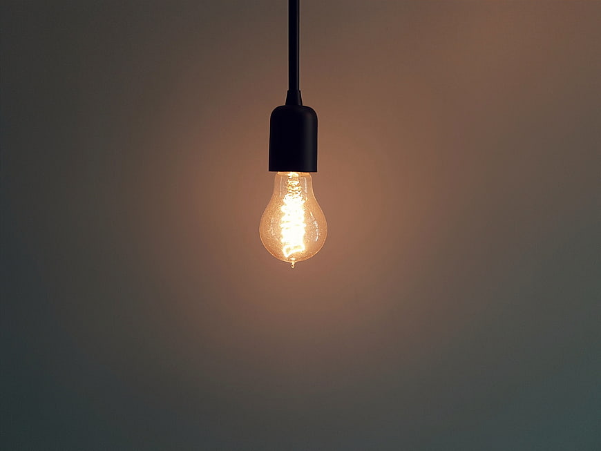 Glowing Edison Bulb Hanging Against Dark Background