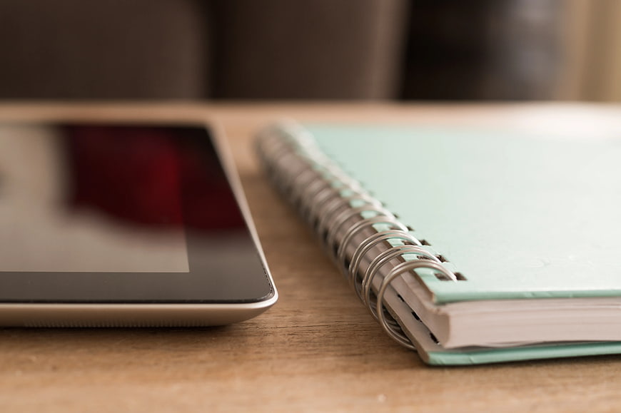 Tablet and Teal Notebook on Wooden Desk