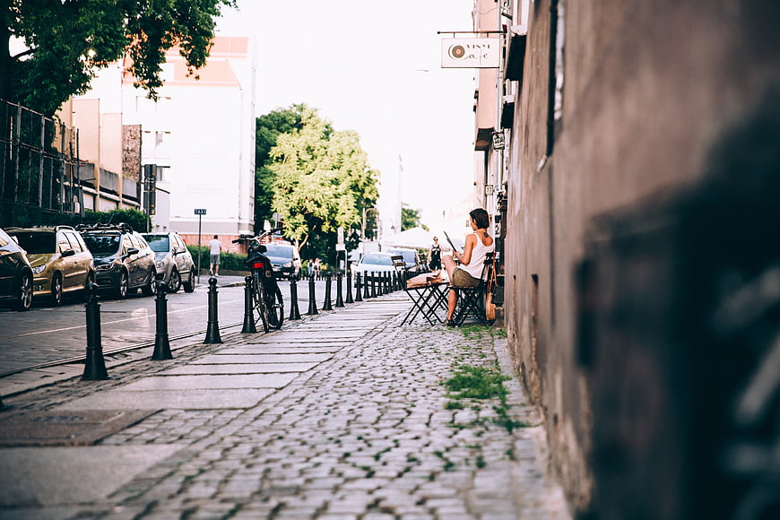 Woman reading newspaper at outdoor cafe on cobblestone street