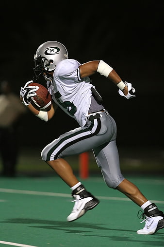 American football player running with ball during night game