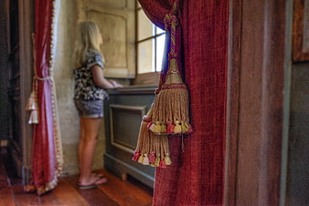 Vintage red curtain tassel with blurred woman looking out window