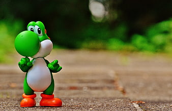 Yoshi toy figure standing on pavement with blurred background